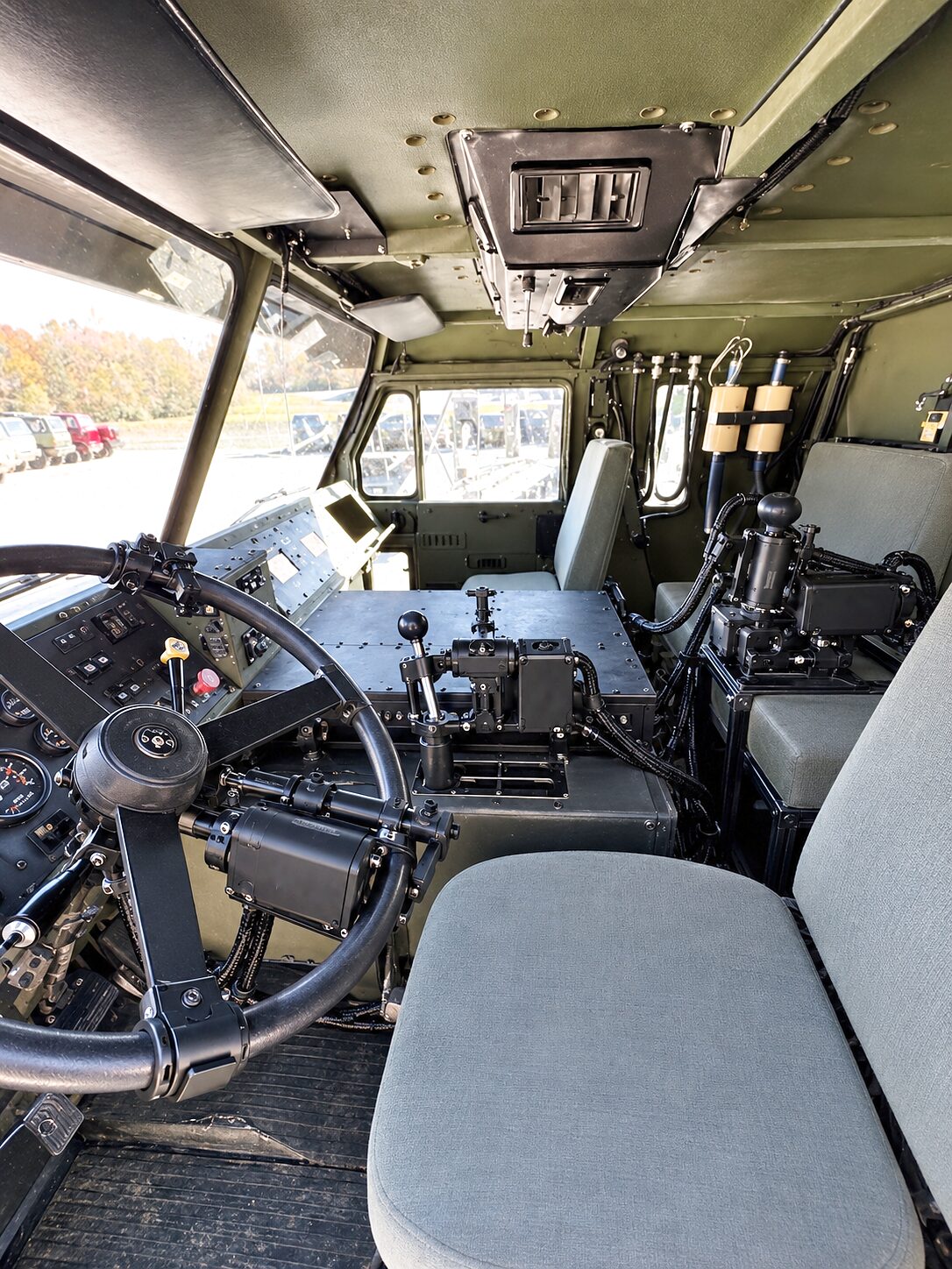 The CDNS Autonomy unit on the steering wheel and the gear levers of a military truck cab, its modules on the wheel and the transmission tunnel, the crew seats behind.