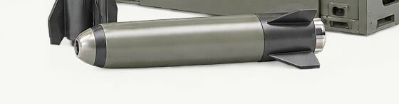 A Goose CS-110 round lying on open ground, its nose at one end and its bonded fin set at the other.