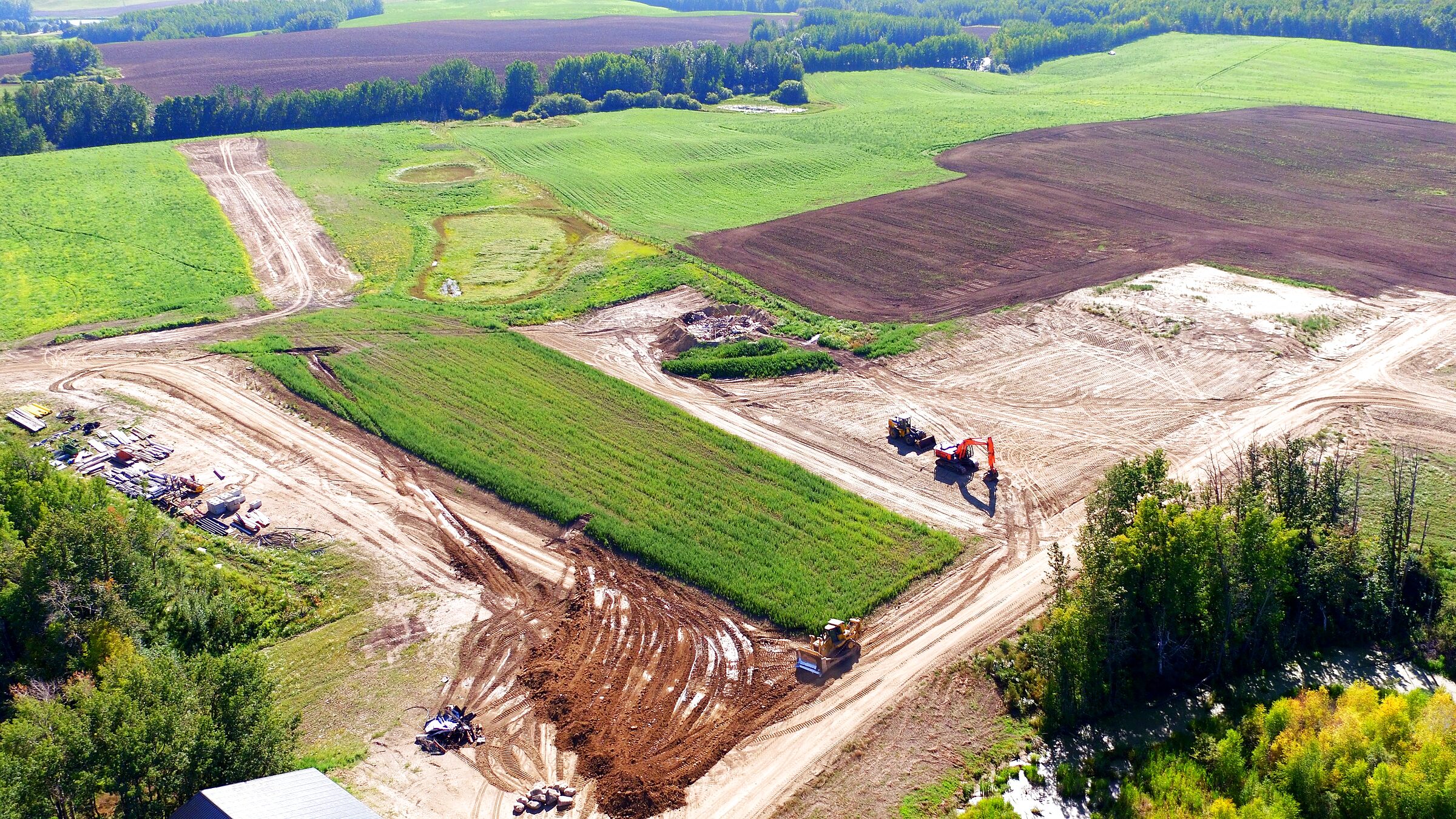 Earthworks on ranch land seen from the air, the cut and the fill laid out across open Alberta ground.