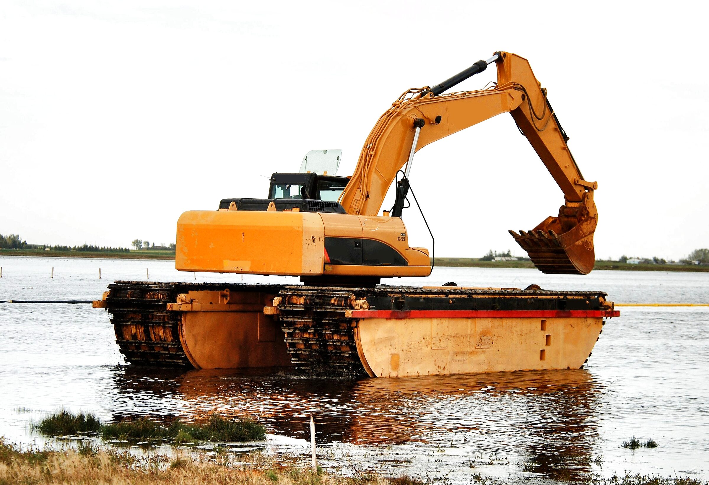 An amphibious excavator on pontoons working open water at Weed Lake, Alberta.